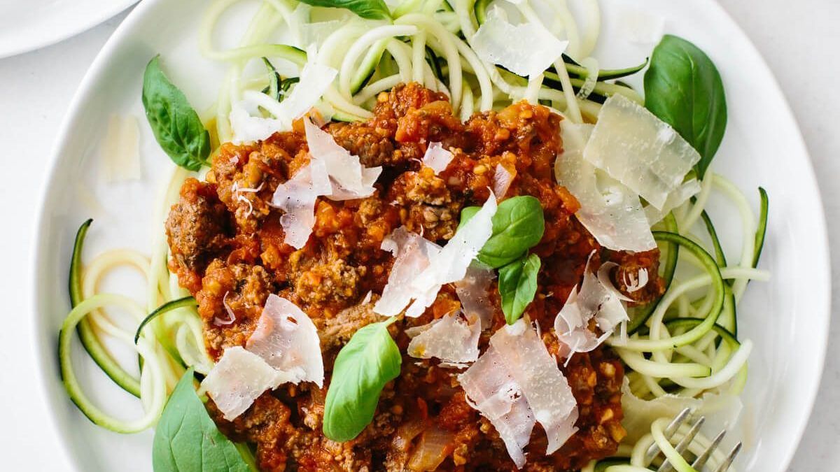 A plate of zucchini noodles topped with bolognese sauce, fresh parmesan and basil.